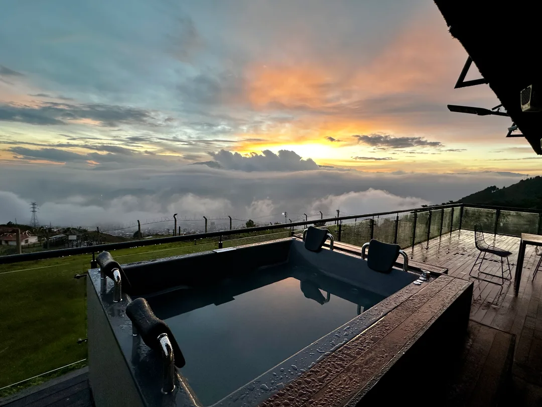 Jacuzzi en la terraza de Prisma San Félix al atardecer, con montañas y nubes iluminadas al fondo